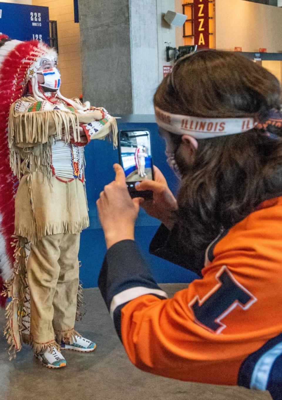 Still from the film of a person photographing a white person dressed as a Native American sports mascot.