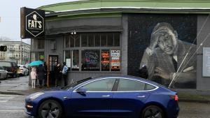 On the side of the building, a black and white mural of Dr. Martin Luther King, Jr. looks forlornly on as a blue Tesla drives by.