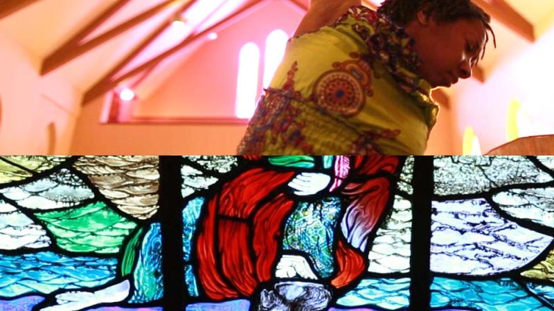 A split image where the top half is a black person from the ribcage up with their arm in the air reaching toward the beams of a vaulted ceiling. The bottom half is an upside down stained glass image of a white Jesus with a red garment against a blue and purple background.