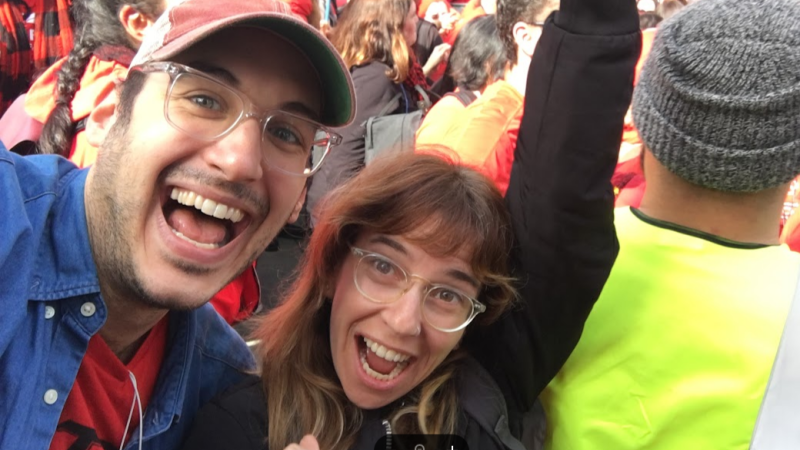 Filmmakers Yael Bridge and Yoni Golijov look up at the camera. They have big smiles and glasses.