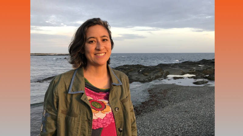 Filmmaker Julie Mallozzi is on the beach with the sun on her face. She is smiling. 