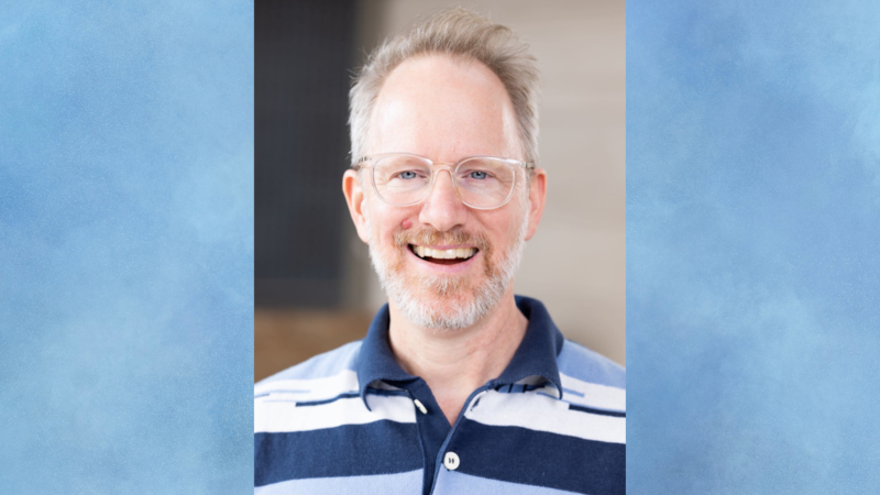 Headshot of filmmaker Kyle Henry, a white man with a graying blond beard and clear-framed glasses, smiling for the camera.