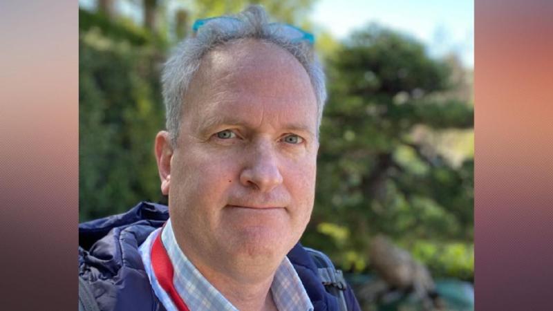 A natural-light outdoor portrait of New Day Films director Charles Abelmann against a softly blurred green backdrop.
