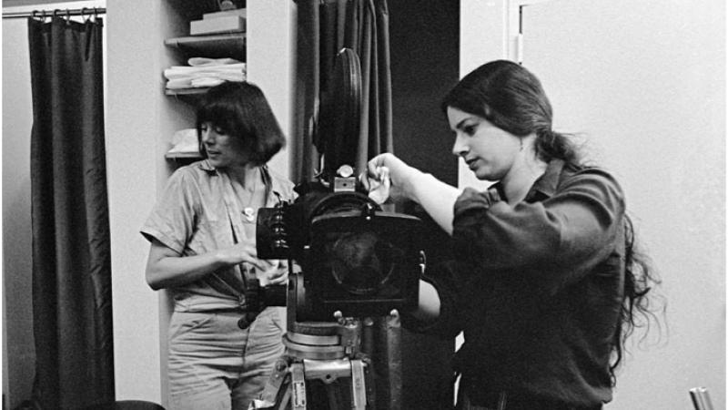 Black and white photo of Amalie Rothschild working on her video camera on an all-women set in the 1970s.