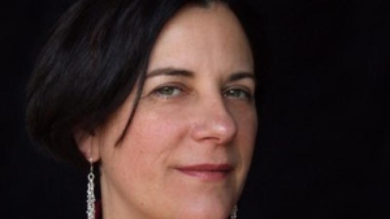 A headshot of the New Day filmmaker Dawn Logsdon. She looks at the camera with a knowing confident smile and she with long dangly earrings.