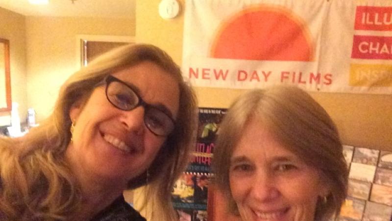 Filmmakers in front of the New Day Films exhibition table smiling for the camera.