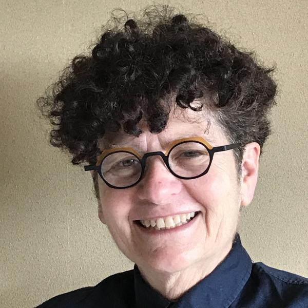 A headshot of Vivian smiling broadly with black oval glasses and dark hair curling upwards.