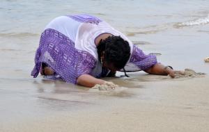 Lucia Ellis bent over in the surf, distraught remembering lost ancestors
