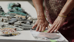 Tess in her studio studying image to reproduce with discarded beach plastic.  