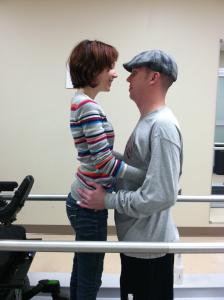 Woman and man facing each other and holding each other inside of parallel bars.