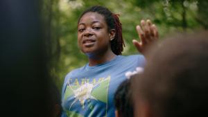 An adult woman addresses a group of school children who will participate in an outdoor activity in the Little Cahaba River. 