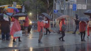 Eight teachers picketing a school gate in the rain during the L.A. teachers strike