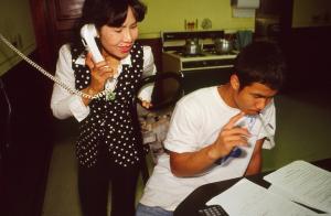 Mother on phone looks over son's shoulder at table