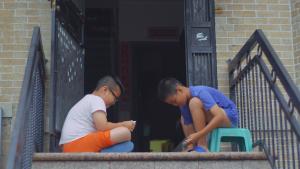 Two kids play cards on a stoop.