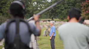 A film crew captures a scene in a cemetery