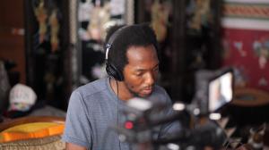 A Black man with headphones and film equipment