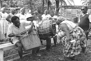 A woman is blowing smoke into a drum in preparation for the ancestor's ceremony 