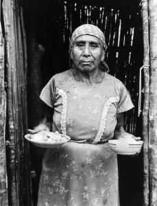 Maya woman holding two bowls of ground corn meal. 