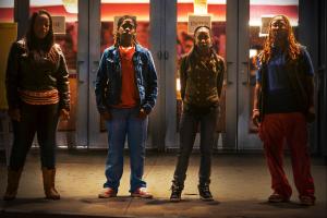 A long shot of four African-Americans who stand looking at the camera.