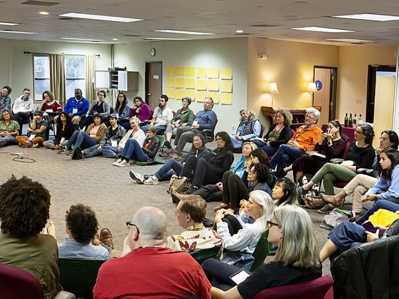 Many filmmakers sitting on the floor of a large room.