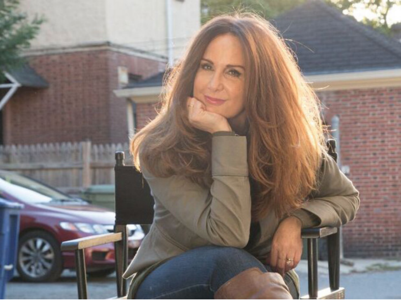 Director Andrea Kalin sits in a director's chair with her hand on her chin, and looks directly at the camera.