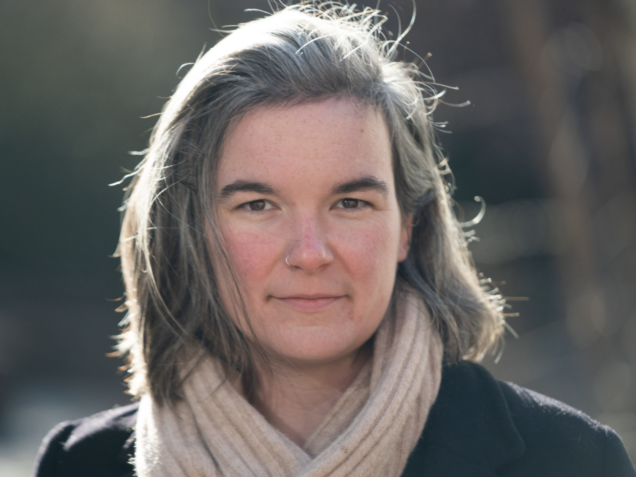 Headshot of Tiffany Fisher-Love, a woman with fair skin and gray medium length hair wearing a beige scarf