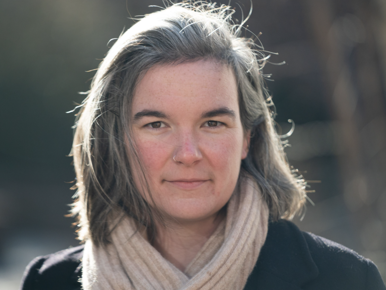 Headshot of woman with fair skin and gray medium length hair wearing a beige scarf