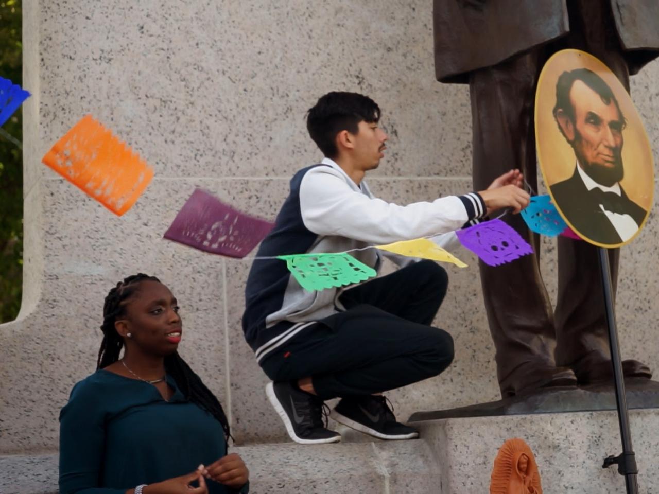 Student kneels next to Abraham Lincoln statue