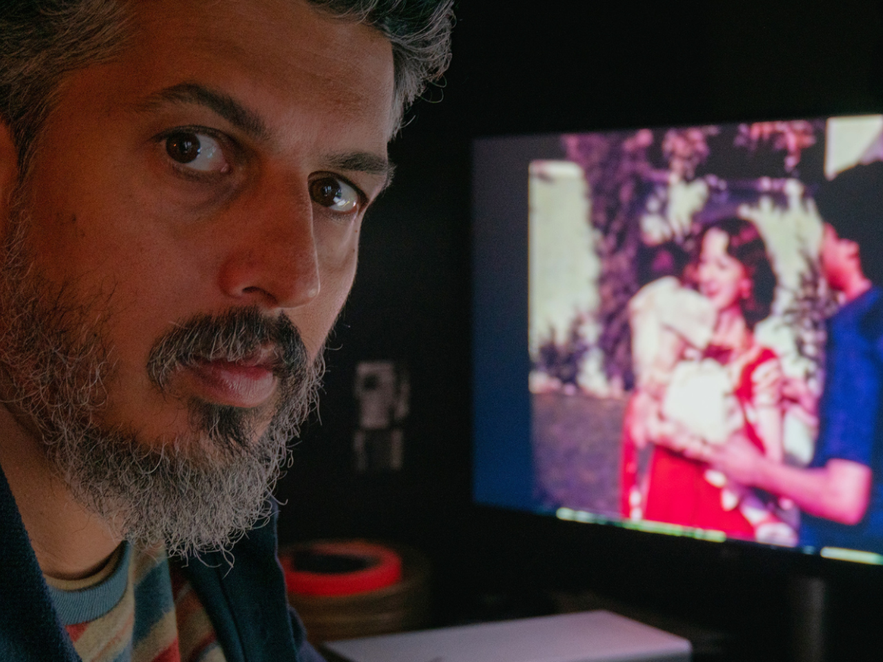 Director Sifian Khan looks at the camera with a television on the background.
