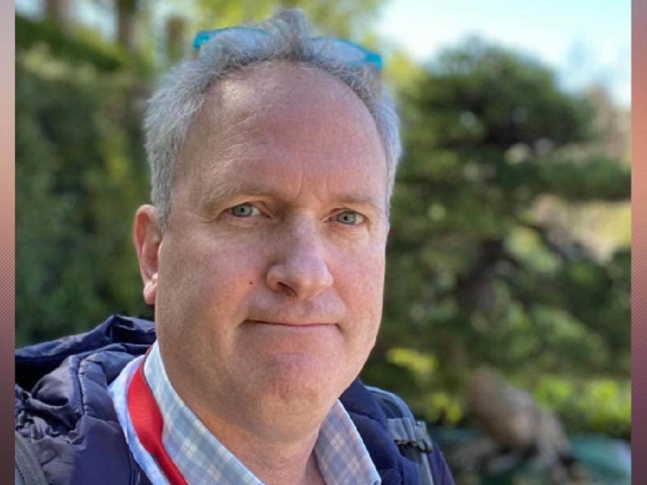 A natural-light outdoor portrait of New Day Films director Charles Abelmann against a softly blurred green backdrop.