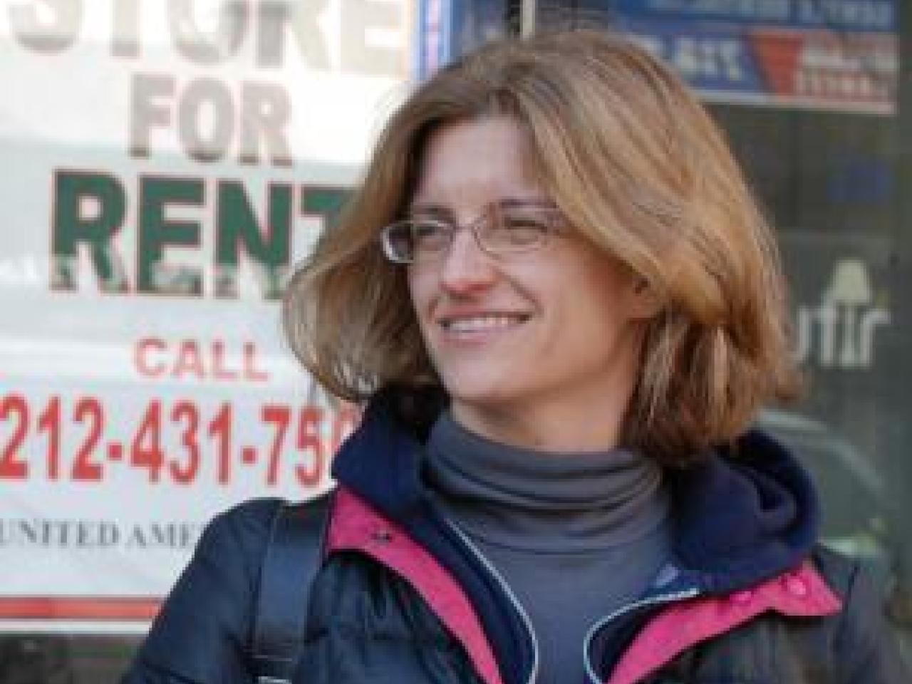 Filmmaker Kelly Anderson outside with a "Store for Rent" sign in the window behind her.