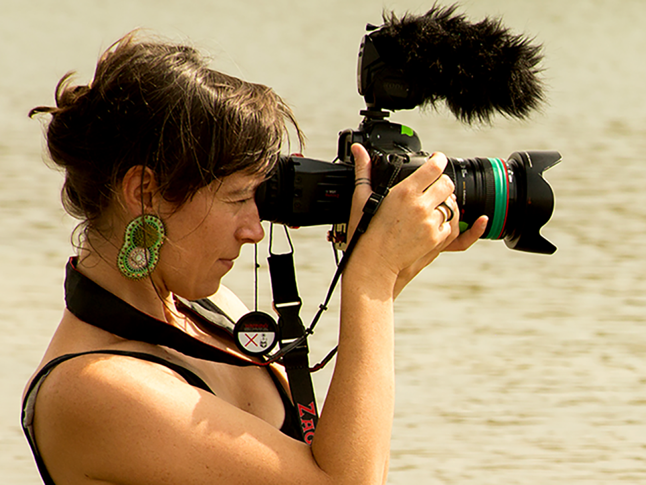 Side view shot of New Day Filmmaker Willow O’Feral, a white woman in her 30s, with dark hair and large earrings, who is looking into a camera.