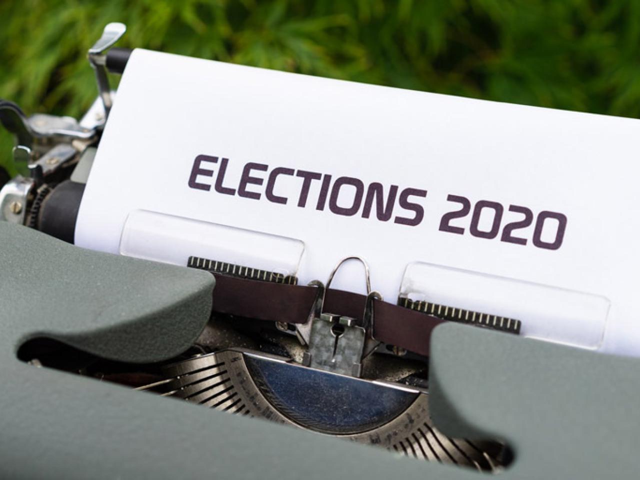Outside, a gray manual typewriter. A sheet of paper in the typewriter reads “Elections 2020” in all capital letters.