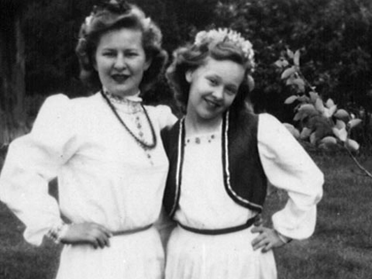 Black and white image from the film Leona's Sister Gerri shows two women in a sidehug outdoors in white dresses.